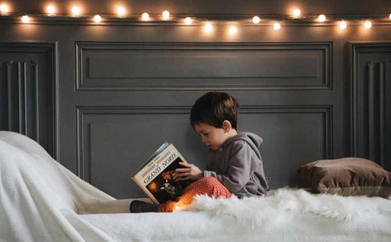 warm twinkle lights and sherpa rug on bed where boy is reading